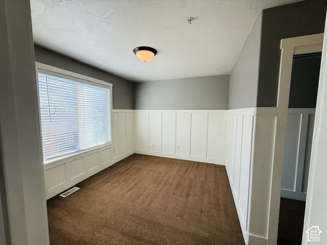 Neutral paint tones with contrasting wainscoting, textured ceiling, and a flush mount light fixture