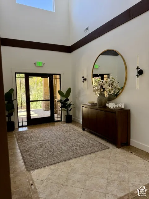Two-story foyer with high ceilings, featuring exposed wood beams and a transom window