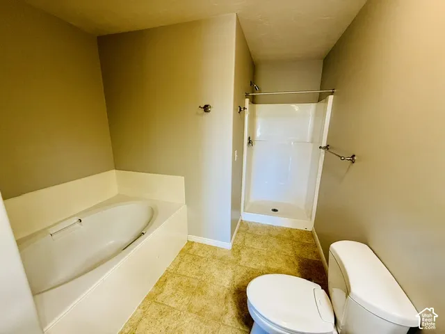 Built-in soaking tub, separate shower stall with chrome fixtures, tiled flooring, and neutral wall paint