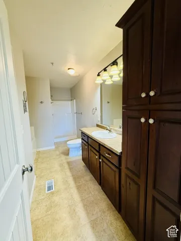 Full vanity with integrated sink, dark wood-finish cabinetry, and overhead sconce lighting
