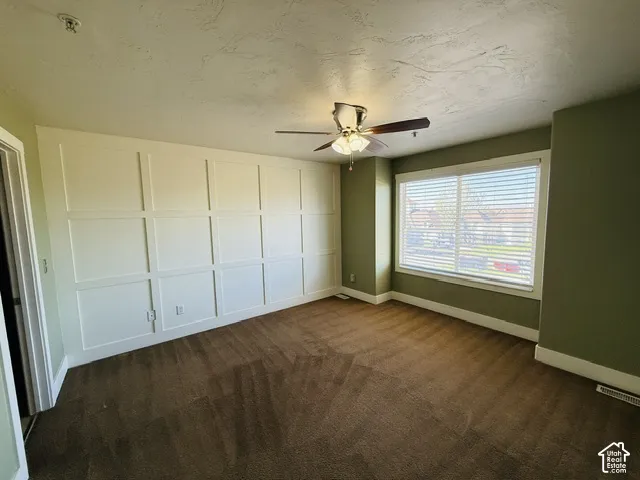 Board and batten accent wall, ceiling fan with light fixture, large window with blinds, and wall-to-wall carpeting