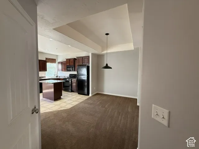 Kitchen featuring wood cabinetry, dark countertops, and a central island with a contrasting top