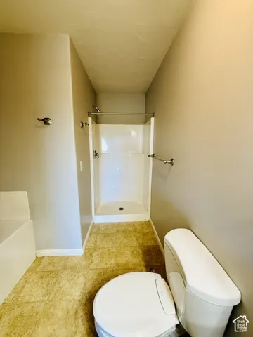 Walk-in shower with white surround, chrome fixtures, and a white toilet