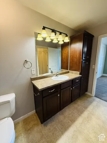 Dark wood-finish vanity with an integrated sink, laminate countertop, and overhead lighting fixture