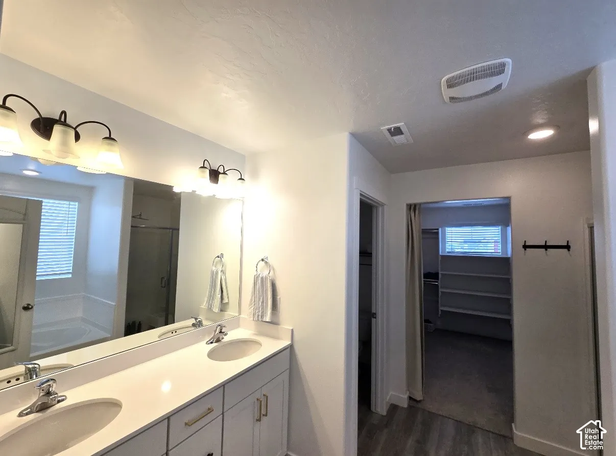 Dual vanity with white cabinetry, gold-finish hardware, and a large mirror