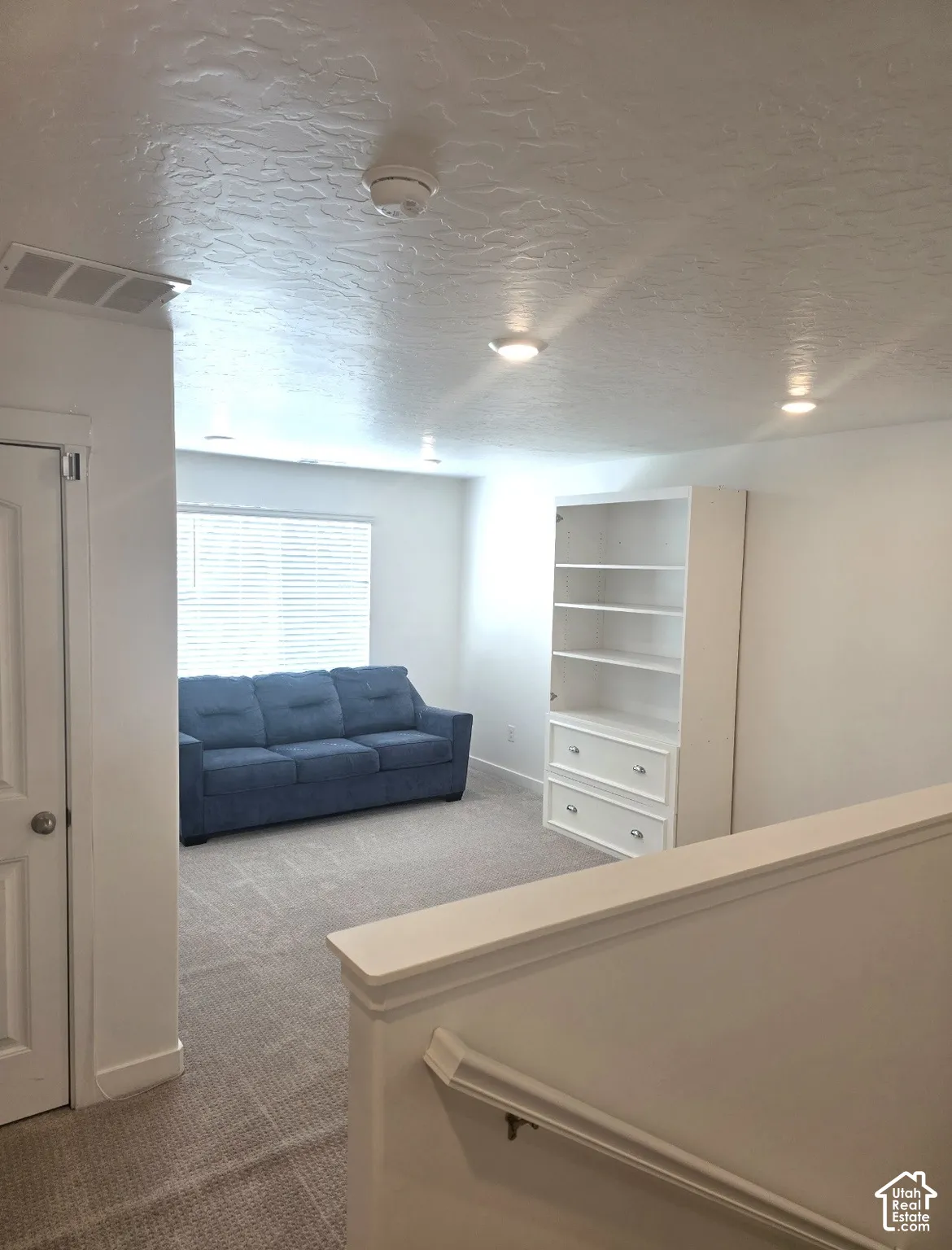 Carpeted area with a built-in bookshelf, recessed lighting, and a window with blinds
