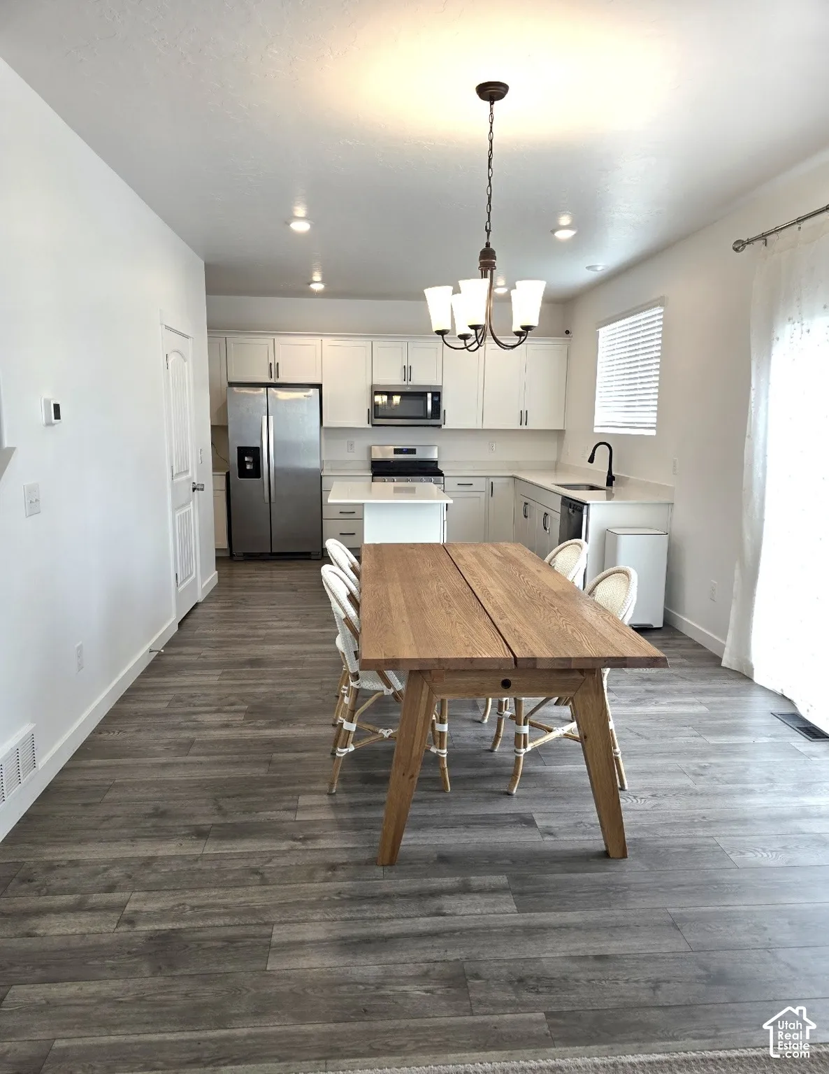 Open-concept living space with wood-finish flooring, recessed lighting, and a chandelier