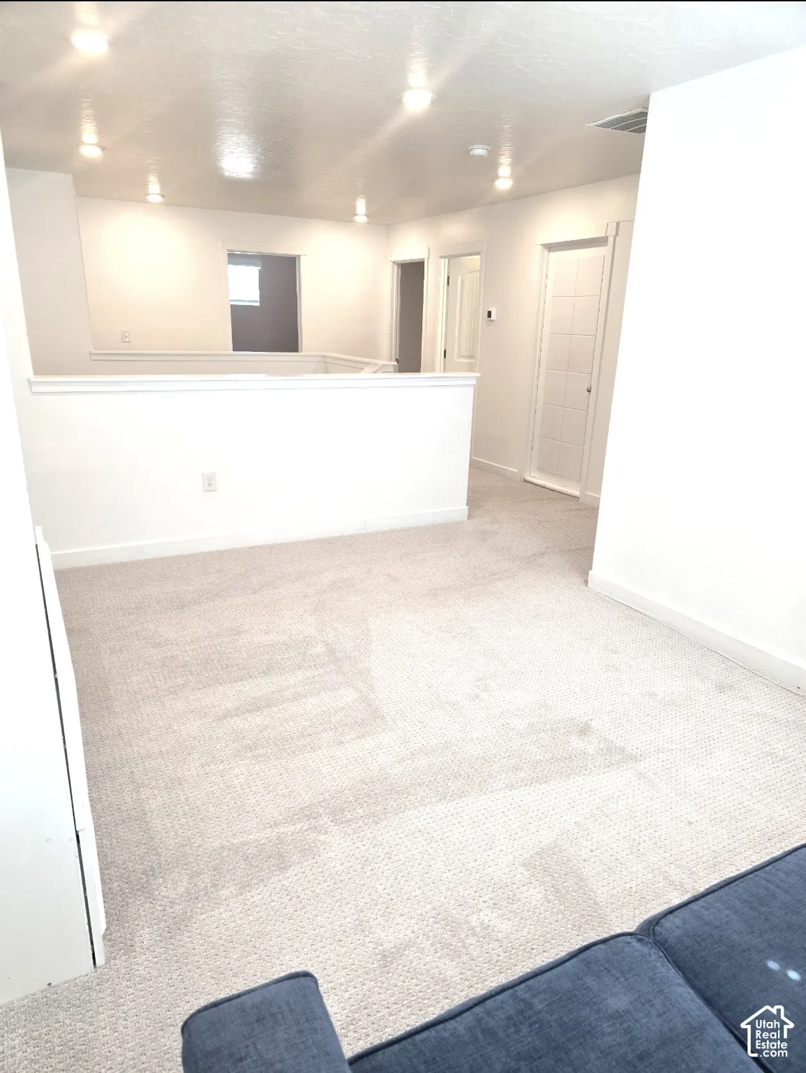 Bright overhead lighting, light-toned carpeting, and white wall finishes