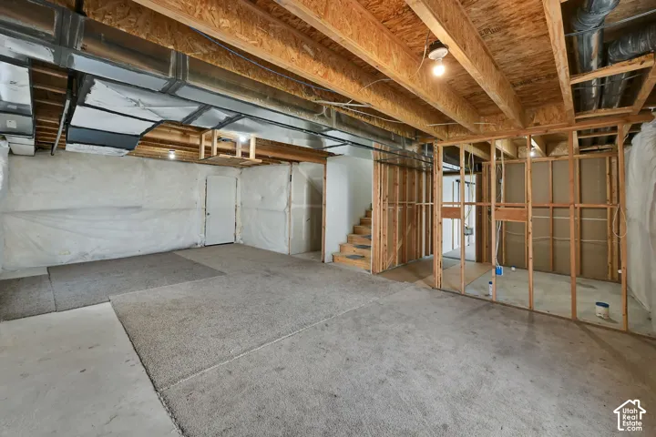 Unfinished basement offering exposed wood joists, concrete flooring, and partial framing for future customization
