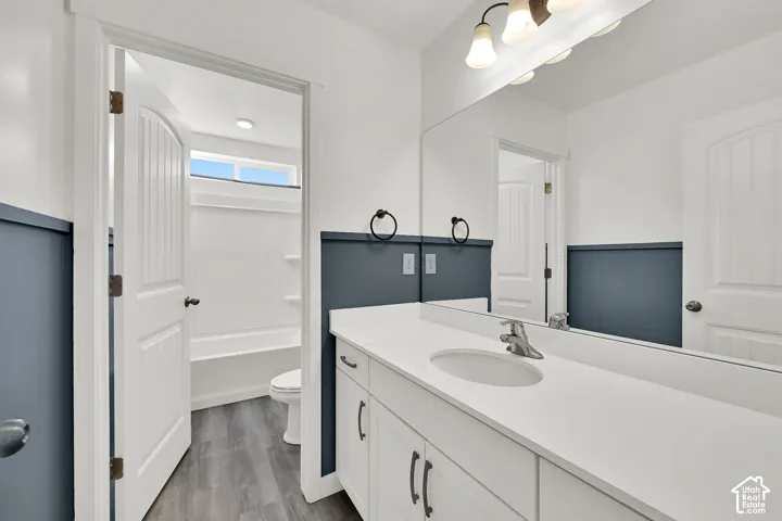 White vanity with a single basin sink, brushed nickel faucet, and a large wall-mounted mirror