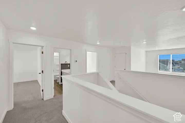 Hallway featuring recessed lighting, white walls, and gray carpeting
