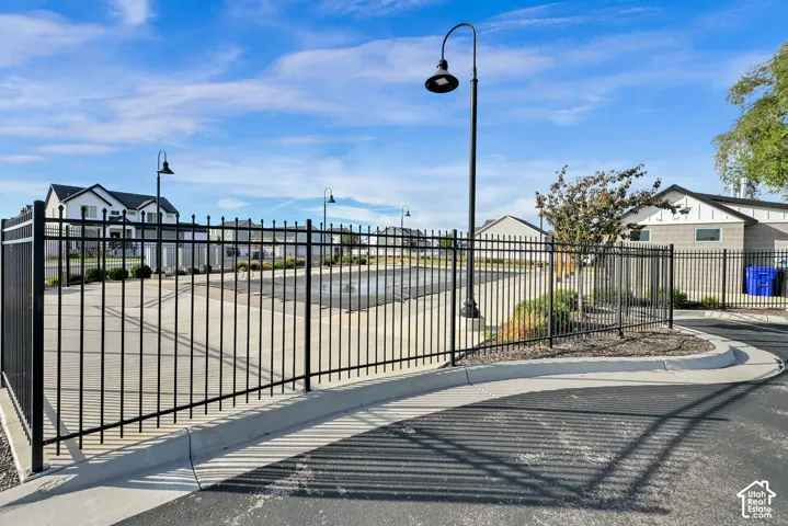 Paved parking lot enclosed by black metal fencing with integrated street lamps and landscaping