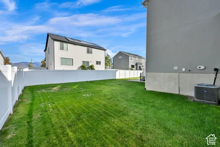 Expansive grassy yard area with a white vinyl fence