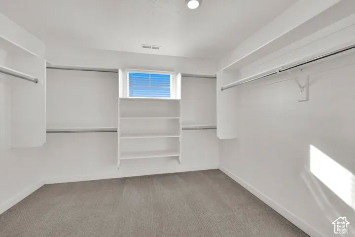 Built-in shelving, two levels of hanging rods, recessed lighting, and a window with blinds