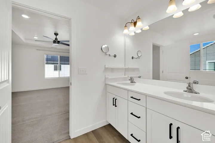 Dual vanity with white cabinetry, matte black hardware, and an expansive wall-mounted mirror
