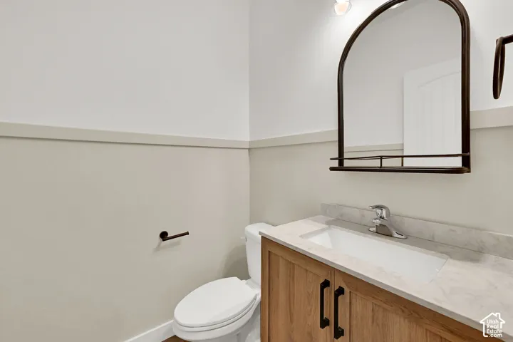 Wood-finish vanity with dual-door cabinetry, a white rectangular sink, and a light-colored countertop