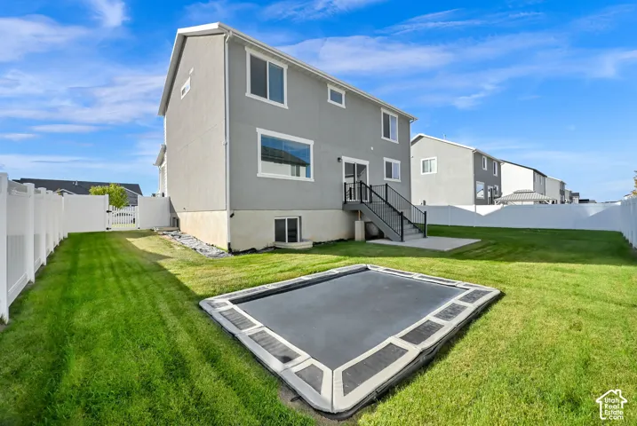Expansive grass lawn with a white vinyl privacy fence and a rear patio