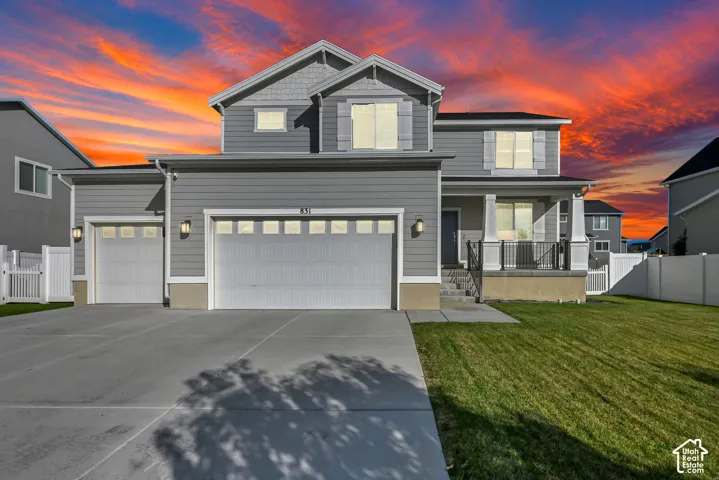 Two-story exterior with gray siding, a covered porch with black railings, and a two-car garage