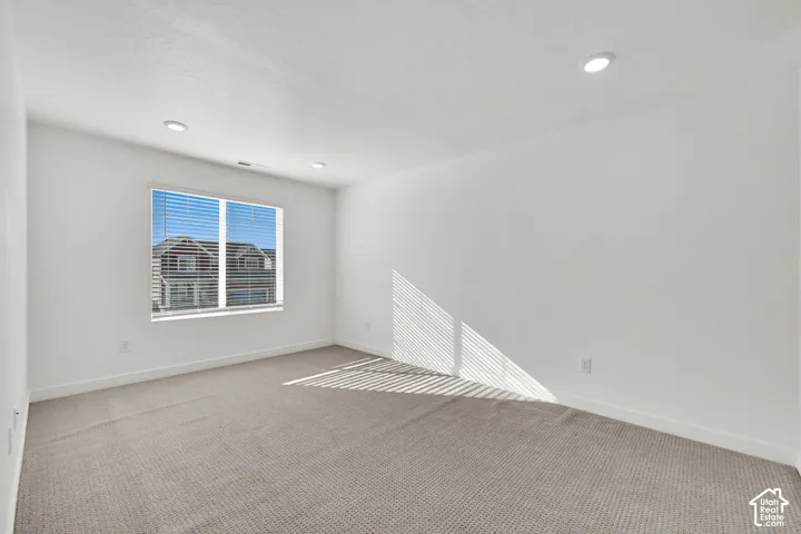 Neutral wall paint, recessed ceiling lighting, light-toned carpeting, and window blinds