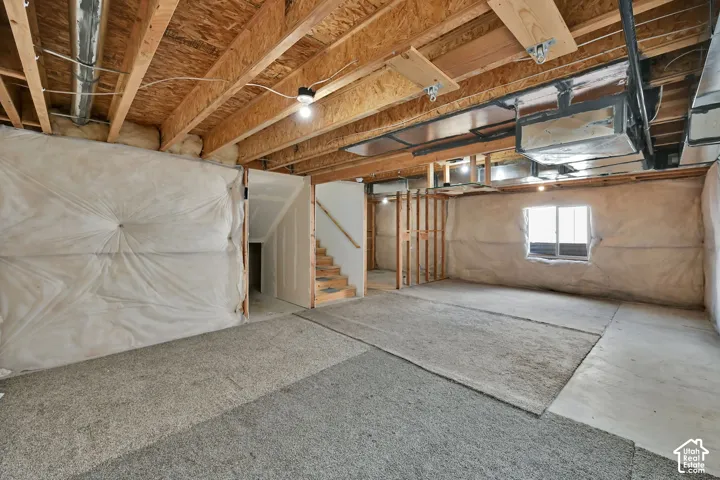 Unfinished lower level with exposed ceiling joists, concrete flooring, and a single window
