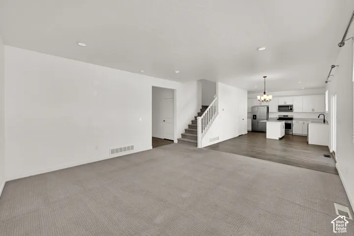 Expansive open-concept living area with light gray carpeting and recessed lighting