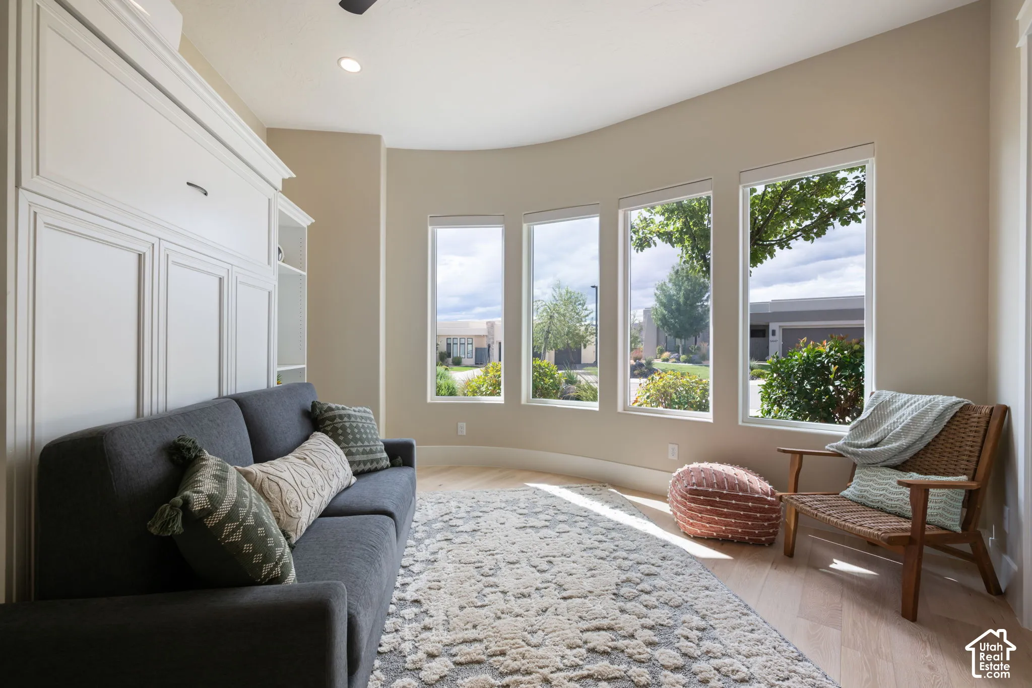 Curved wall with three tall windows, light wood-finish flooring, built-in cabinetry, and recessed lighting
