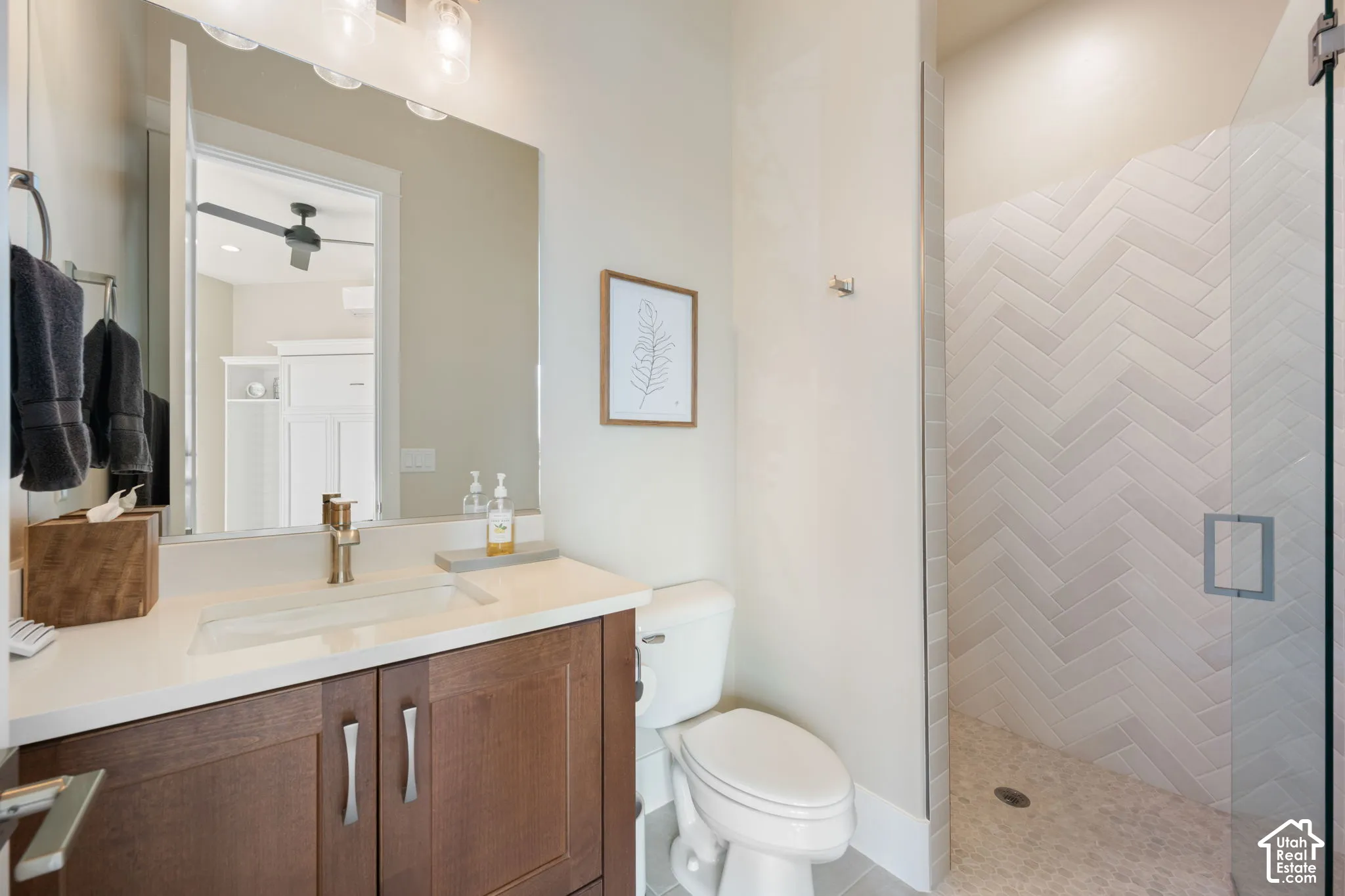 Wood-finish vanity with an integrated rectangular sink, gold-tone faucet, and white countertop