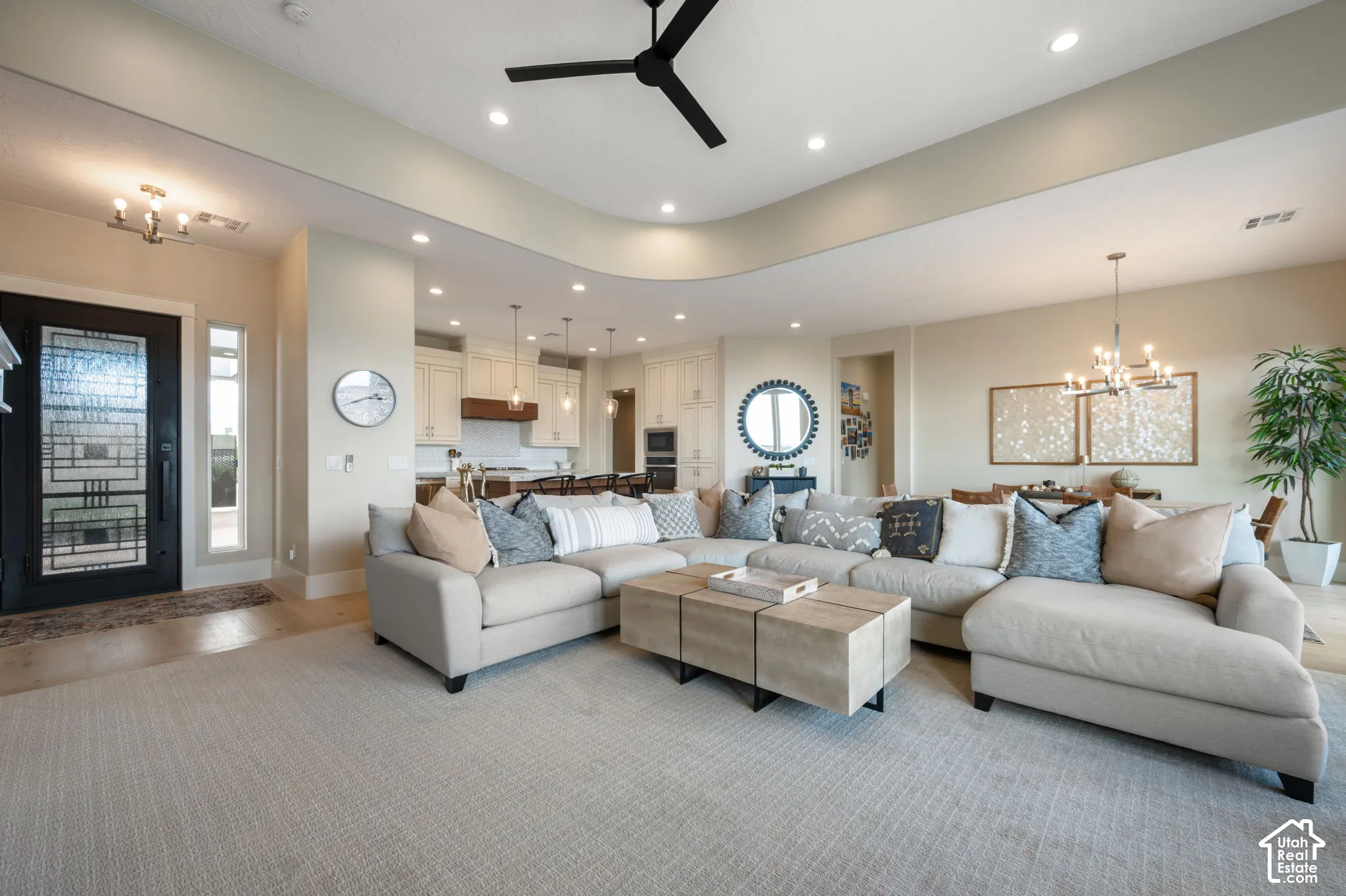 Spacious open-concept living area featuring neutral upholstery, wood-finish flooring throughout, and abundant recessed lighting