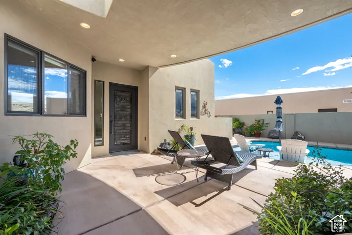 Covered patio with recessed lighting, an exterior entry door with an ornate iron insert, and a private pool
