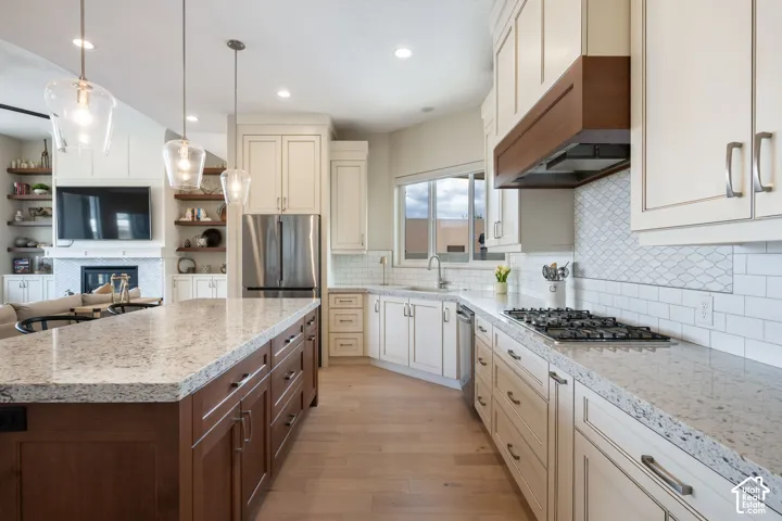 Kitchen featuring an expansive island with a light-toned countertop, wood-finish cabinetry, and three pendant light fixtures