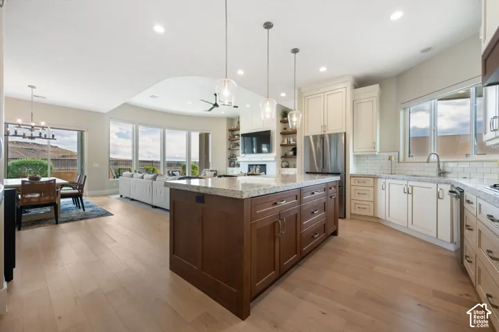 Gourmet kitchen with a large island, wood-finish flooring, and white cabinetry
