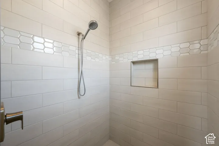 Subway tile shower surround with an accent band of hexagonal tiles, built-in shower niche, and a handheld shower fixture