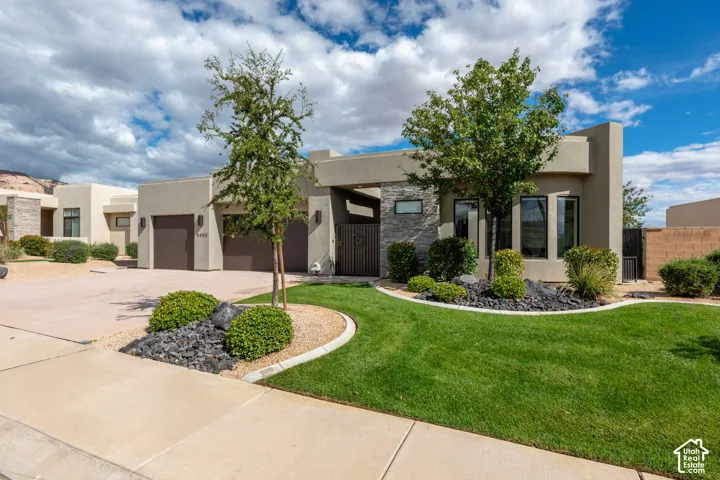 Contemporary exterior with stucco finish, stone accents, two-car garage, and manicured lawn