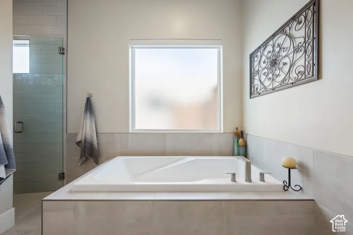 Built-in soaking tub with brushed nickel fixtures, surrounded by large format tile