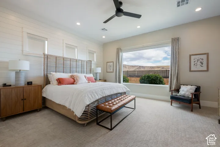 Wall-mounted recessed lighting, ceiling fan, shiplap accent wall, large picture window with desert scenery, and neutral-toned carpeting