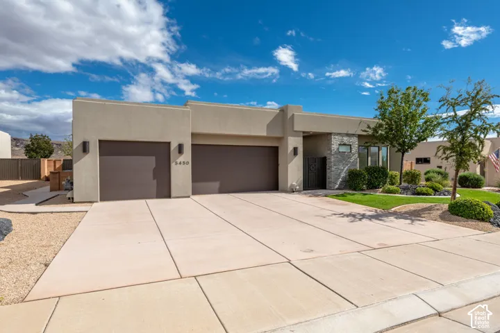Stucco exterior with stone accents, two-car garage, and established landscaping
