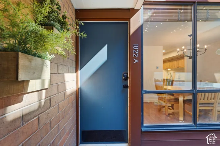Modern entry featuring a striking cobalt blue door with geometric light detail, flanked by warm brick exterior and large multi-pane glass storefront windows