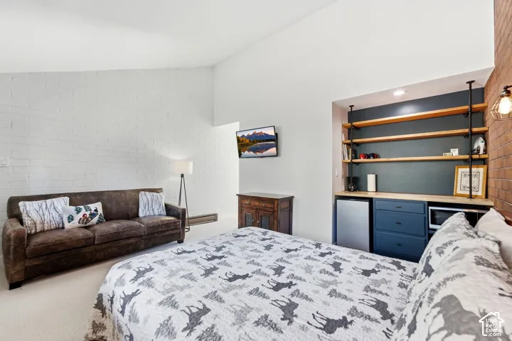 White painted brick wall, built-in shelving with wood-finish shelves, blue cabinetry with a light wood-finish countertop, and exposed brick accent wall