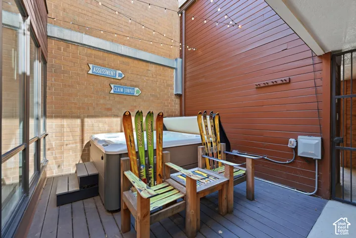 Outdoor deck featuring a built-in hot tub, dark-stained wood-finish decking, and string lighting