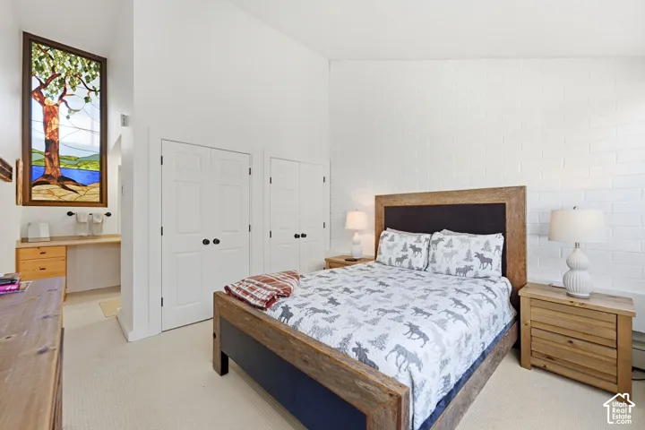 Vaulted ceilings, a distinctive stained glass window, white painted brick accent wall, built-in desk, and two paneled doors