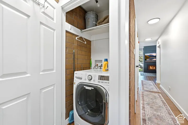 Compact laundry area with brick-patterned wall and integrated shelving