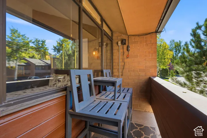 Covered patio with brick exterior walls, large fixed windows, and blue wood-finish seating