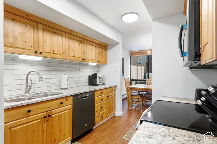 Kitchen featuring wood cabinetry, light-toned countertops, a subway tile backsplash, and a stainless steel double basin sink
