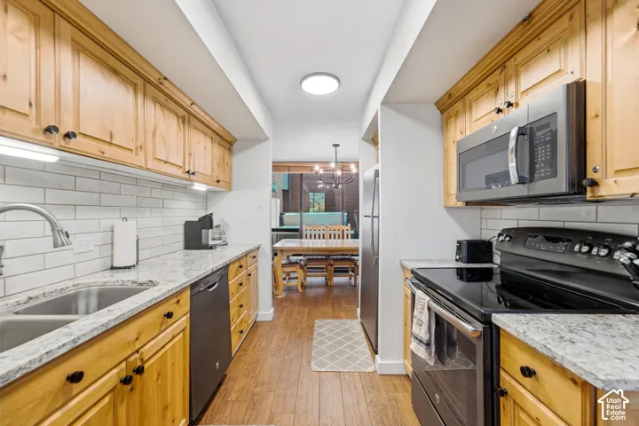 Galley kitchen featuring wood cabinetry, light-toned countertops, subway tile backsplash, and stainless steel appliances
