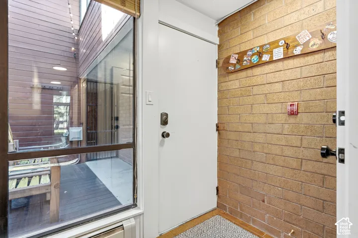 Entryway featuring a solid door, exposed brick wall, and patterned flooring