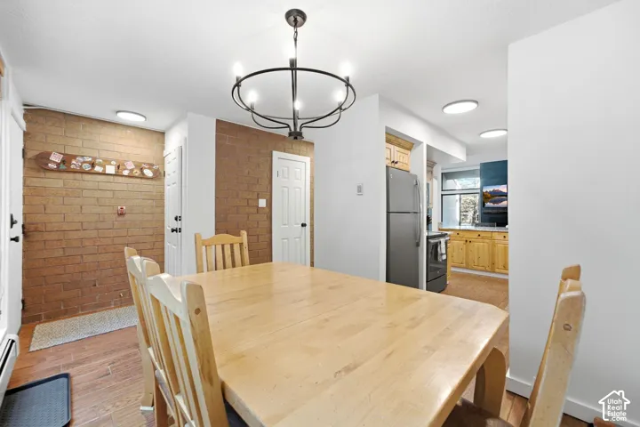 Hardwood-finish flooring, exposed brick accent wall, modern black chandelier, white paneled doors, and recessed lighting