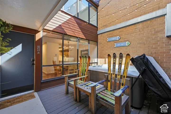 Outdoor decking with a built-in hot tub, brick accent wall, and large glass windows