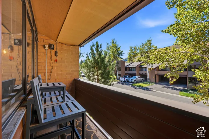 Balcony with brick wall, glass paneling, and wood-finish railing