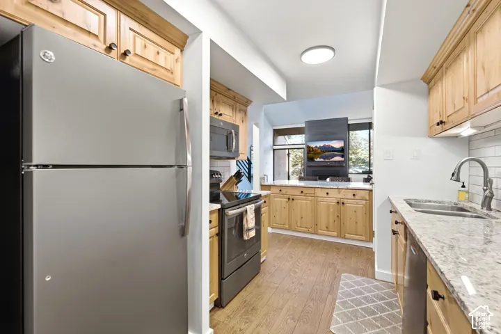Stainless steel appliances, wood-finish flooring, light-toned cabinetry, granite-style countertops, and subway tile backsplash