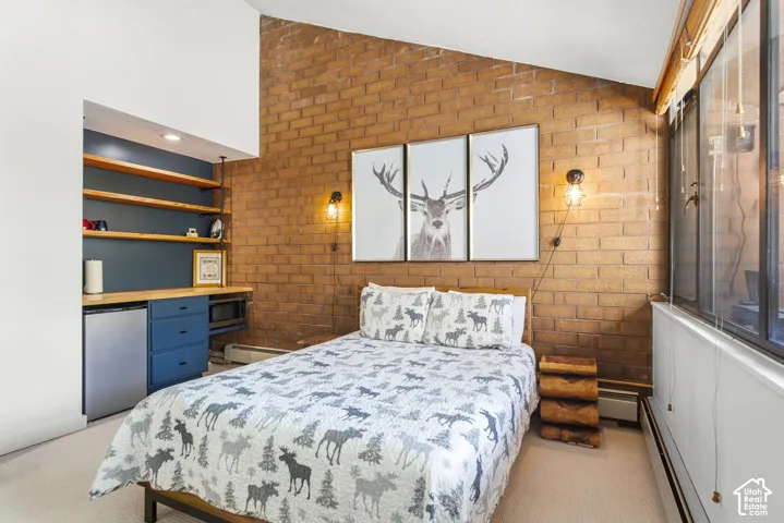 Exposed brick accent wall, built-in shelving, integrated cabinetry, durable flooring, and large windows